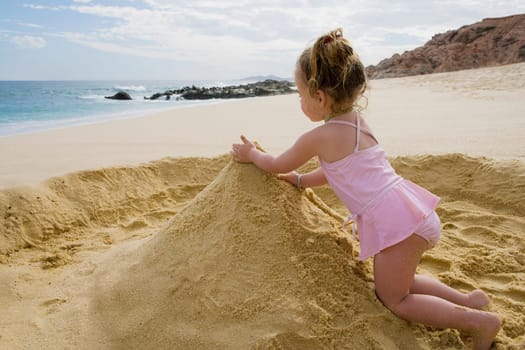 Baby girl playing with sand on the beach, Cabo San Lucas, Mexico
