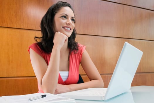 Businesswoman dreaming in front of a laptop smiling