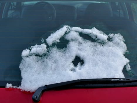snow on a rear window of a red car