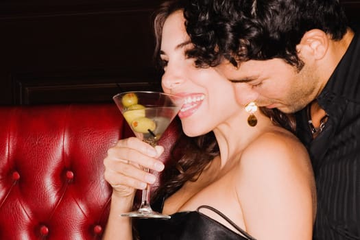 Close_up of a young man sitting on a booth and embracing a mid adult woman