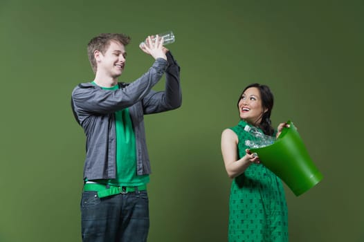 Woman holding a recycling bin and a man looking into an empty water bottle