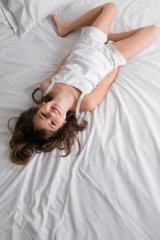 High angle view of a girl lying on the bed and smiling