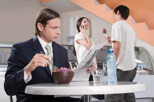 Businessman reading a newspaper in an ice cream parlor