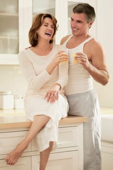 Couple drinking juice and romancing in the kitchen