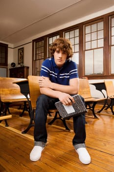 Teenage boy holding a book and sitting in a classroom