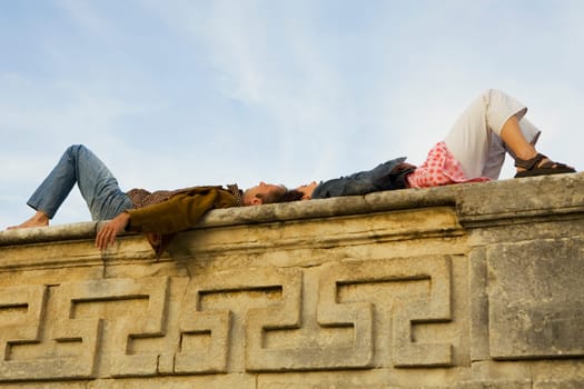 Low angle view of a young couple lying on a stone wall