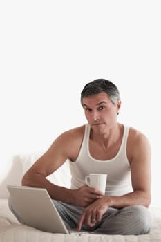 Portrait of a man working on a laptop on the bed
