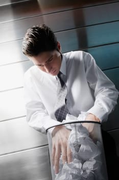 Businessman searching in a wastepaper basket
