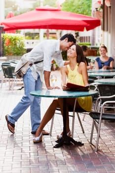 Side profile of a young woman whispering into a young womanŽs ear in a sidewalk cafe