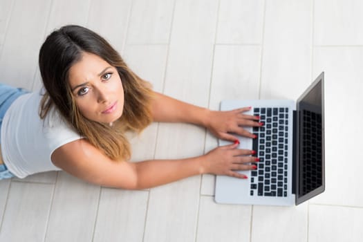 Beautiful young woman relaxing at home on her laptop computer