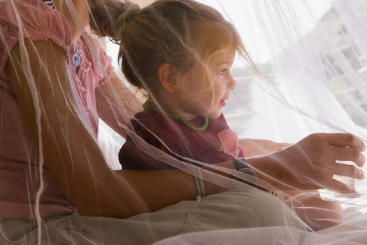 Baby girl sitting with her mother in the bedroom