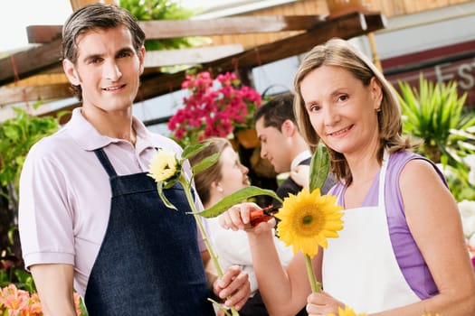 Woman pruning flowers with a man standing beside her