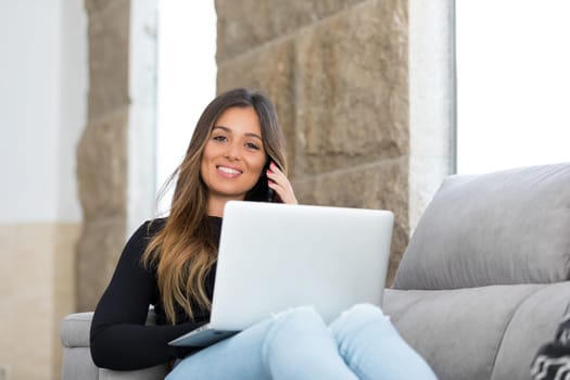 Beautiful young woman relaxing at home on her laptop computer