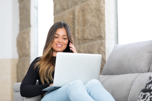 Beautiful young woman relaxing at home on her laptop computer