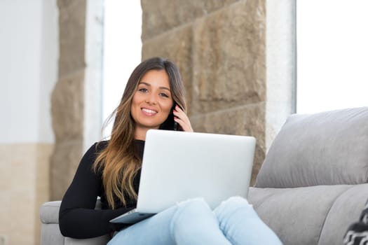 Beautiful young woman relaxing at home on her laptop computer