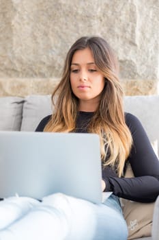 Beautiful young woman relaxing at home on her laptop computer