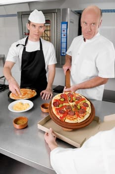 Three chefs preparing pizza in the kitchen