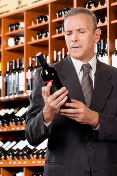 Businessman reading the label of a wine bottle