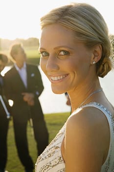 Portrait of a bride smiling with two golfers in the background, Biltmore Golf Course, Coral Gables, Florida, USA