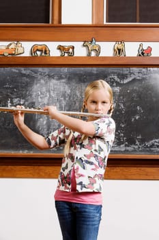 Schoolgirl playing a flute in a classroom