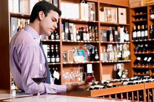 Businessman leaning on a bar counter and holding a rose