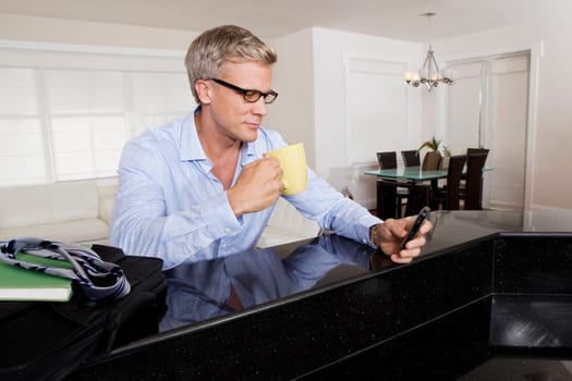 Man drinking coffee and text messaging on a mobile phone