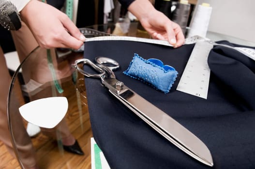 Female tailor taking measurement in a clothing store