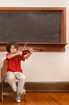 Schoolboy playing a violin in a classroom