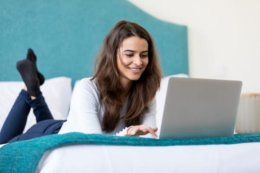 Beautiful young woman relaxing at home on her laptop computer
