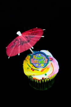 Close_up of a birthday cake with a drink umbrella
