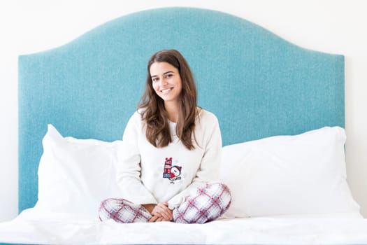 Beautiful happy young woman relaxing in bed