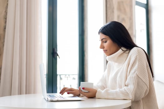 Beautiful young woman relaxing at home on her laptop computer