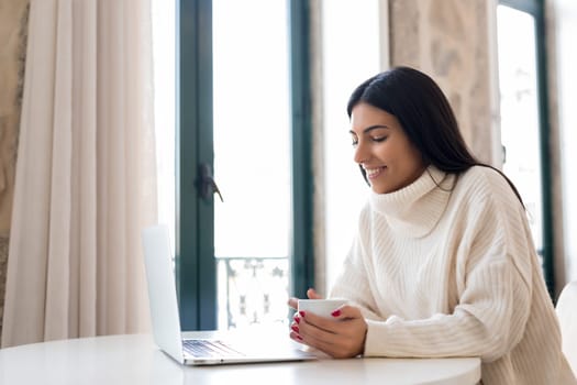 Beautiful young woman relaxing at home on her laptop computer