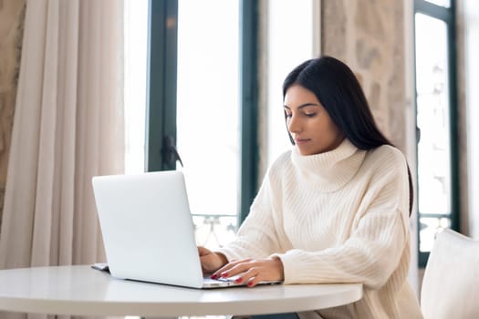 Beautiful young woman relaxing at home on her laptop computer