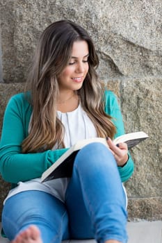 Beautiful young woman relaxing at home reading a book