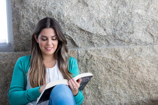 Beautiful young woman relaxing at home reading a book