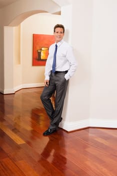 Businessman leaning against a wall in a house