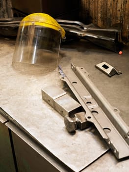 Close_up of a metal object and a helmet visor on a workbench
