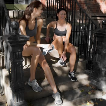 Two women sitting on steps and smiling