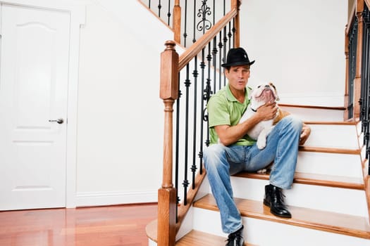 Man sitting on a staircase and carrying his dog