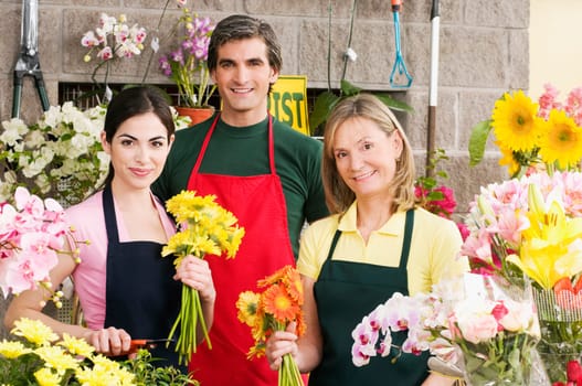 Two female florists with a male florist smiling