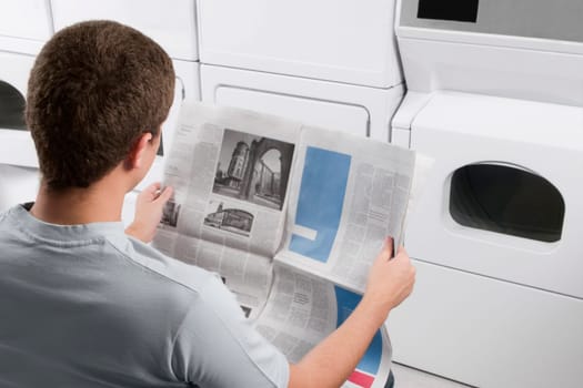 Man reading a newspaper in a laundromat