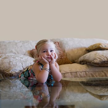 Baby girl leaning on elbows on the glass table
