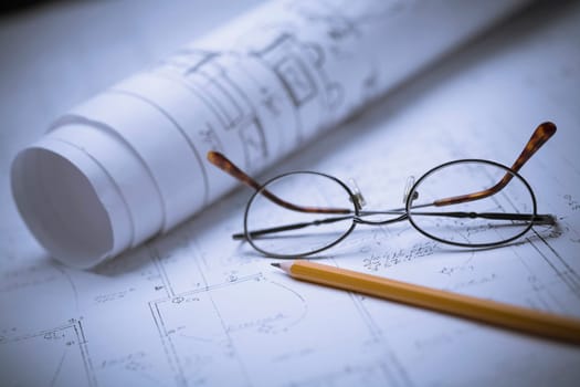 Close_up of eyeglasses and a pencil on a blueprint