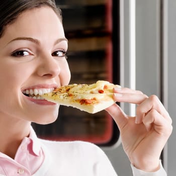 Female chef eating a slice of pizza