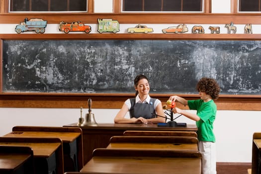 Schoolboy and his teacher with model of solar system in a classroom