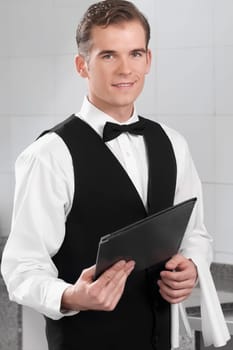 Portrait of a waiter holding a menu in a restaurant