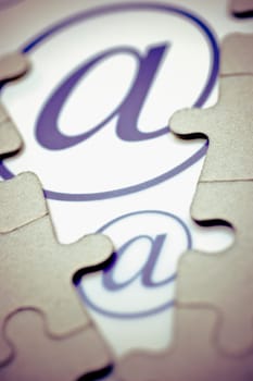 Close_up of at symbol between jigsaw pieces