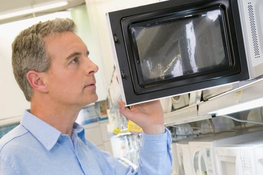 Man looking at a microwave oven in a supermarket