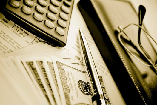 Close_up of a pen with a calculator and eyeglasses on a financial newspaper